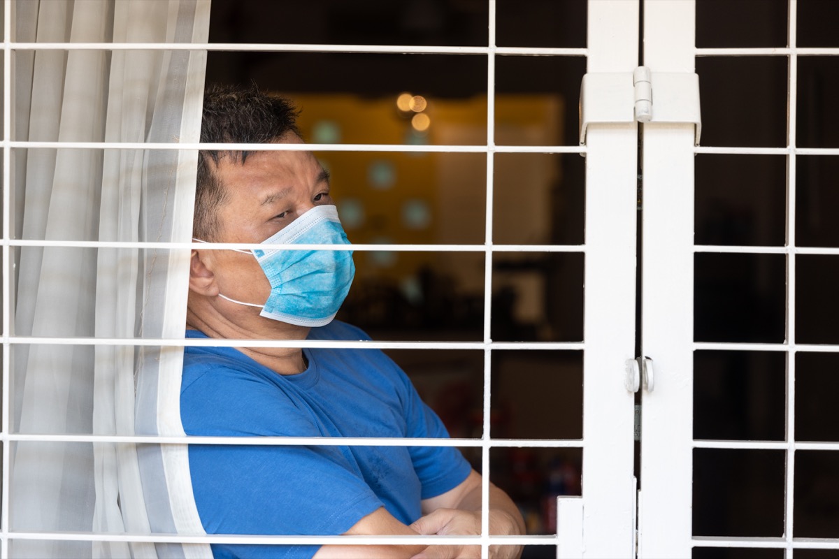 man looking out window as he's quarantined