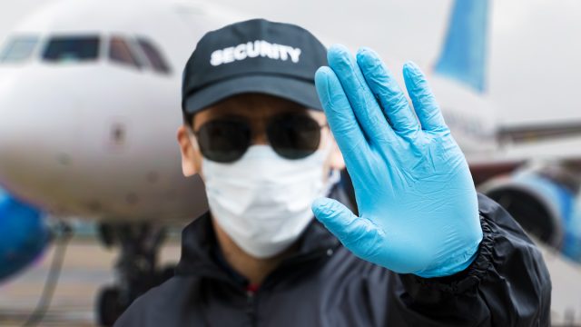 Security guard with face mask in front of airplane