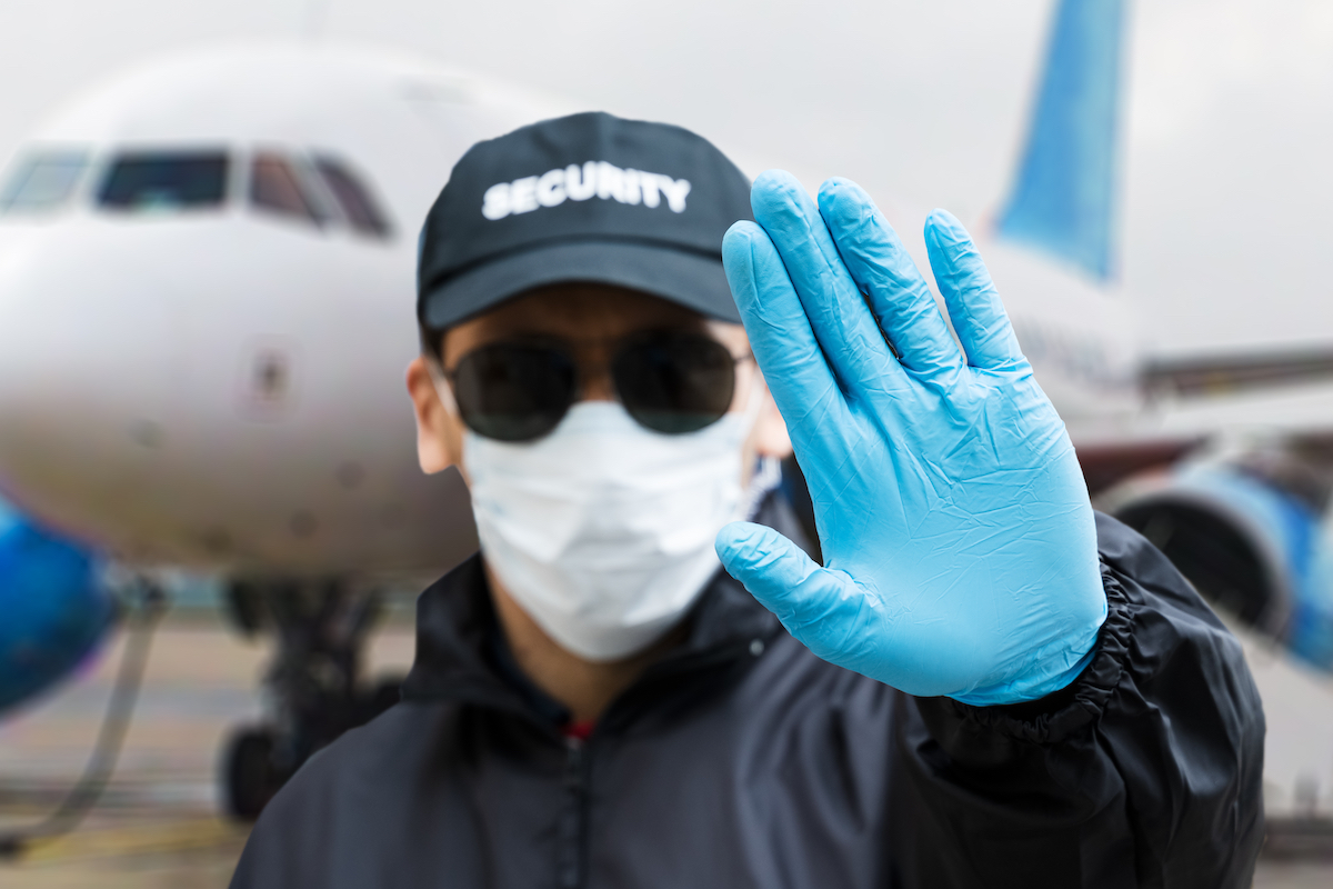 Security guard with face mask in front of airplane