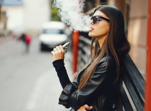 young white woman smoking an e-cigarette outside