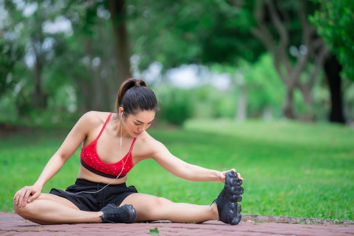 young asian woman stretching in a park