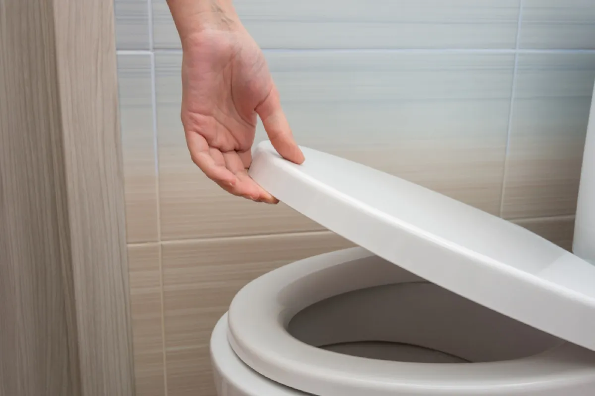 close up of hand lowering toilet seat