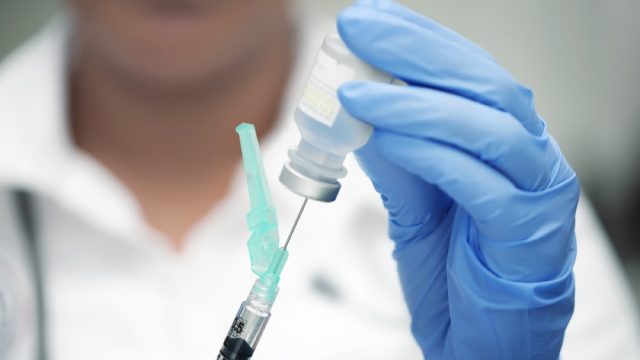 close up of doctor using needle to draw out vaccine