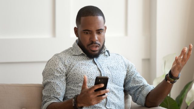young black man confused while looking at phone