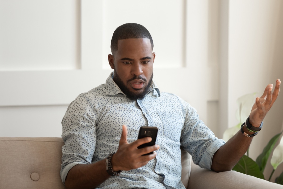 young black man confused while looking at phone