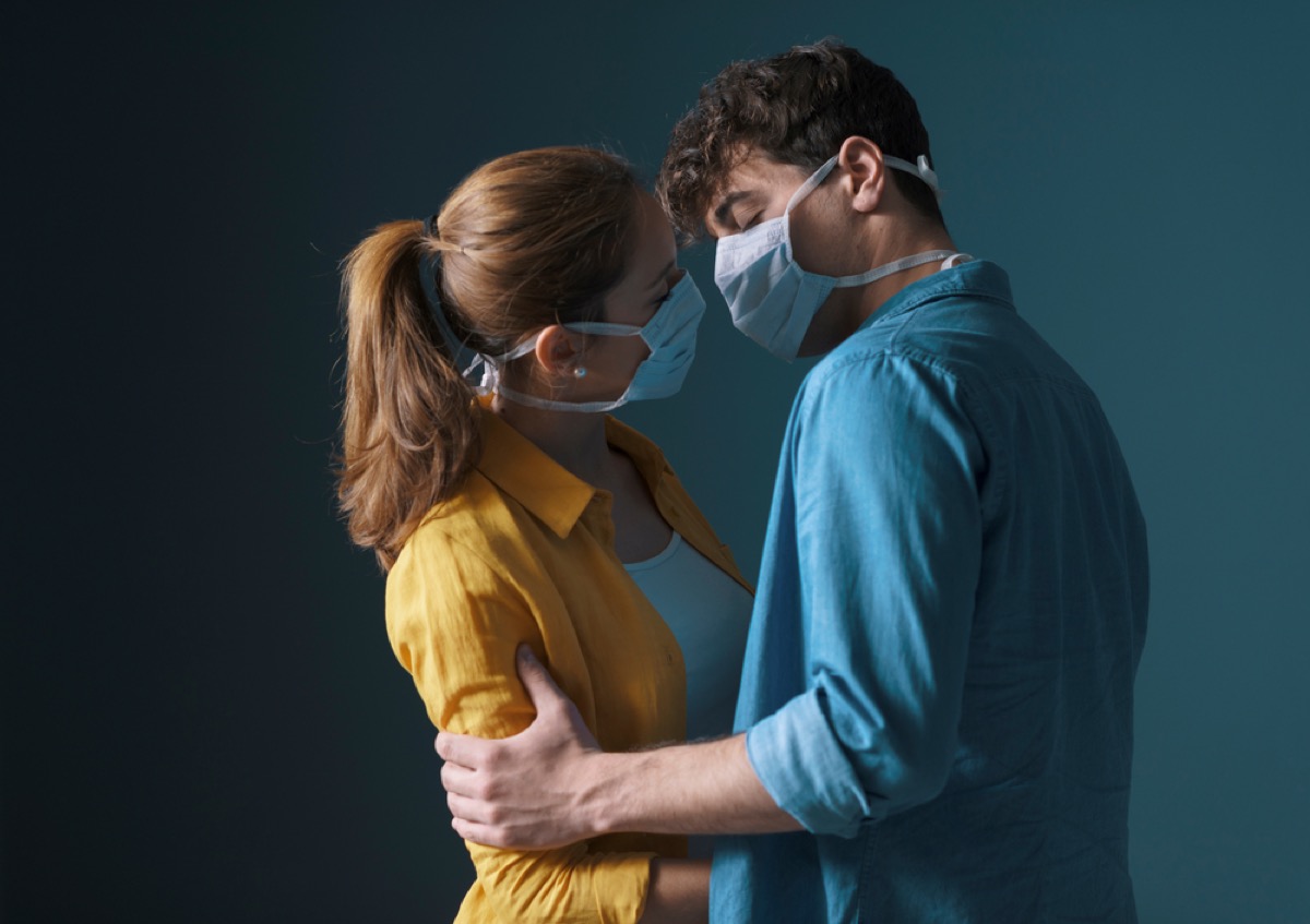 young white woman and young white man embracing with face masks