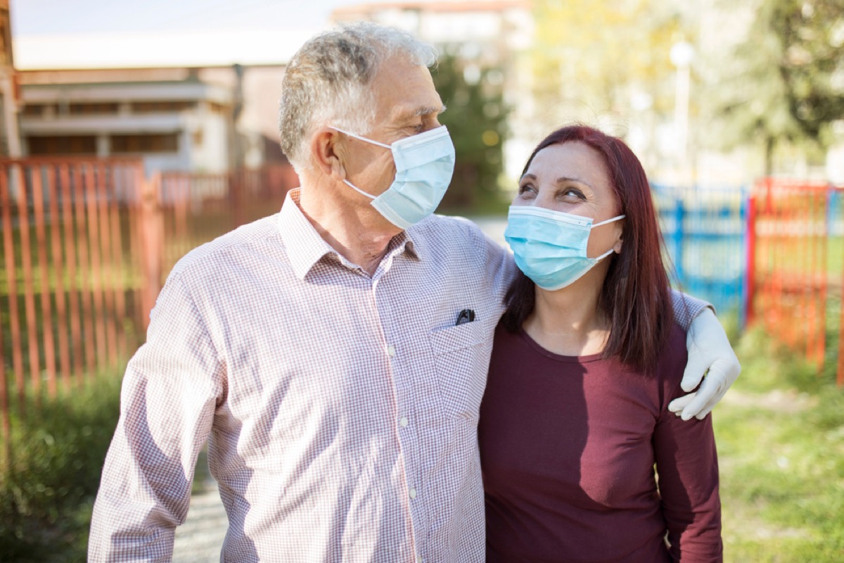 older white man with face mask with his arm around older white woman with face mask