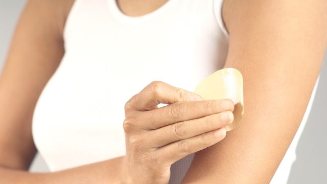 close up of woman applying patch to her arm