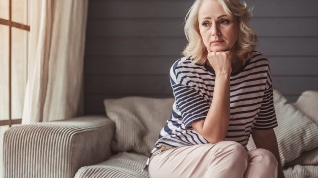 sad older white woman sitting on a couch