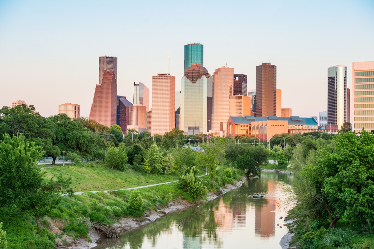 This is a photograph of Buffalo Bayou park with a stream leading towards the buildings in downtown Houston, Texas in spring.