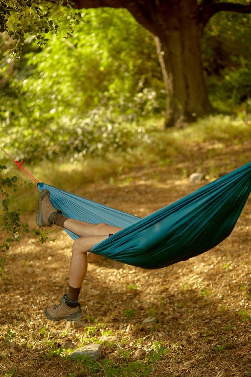 white person in travel hammock outside