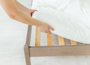 white hands putting sheet on bed