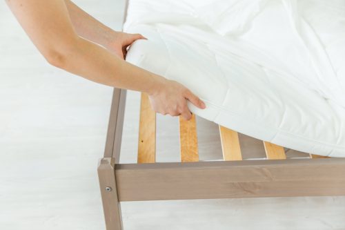 white hands putting sheet on bed