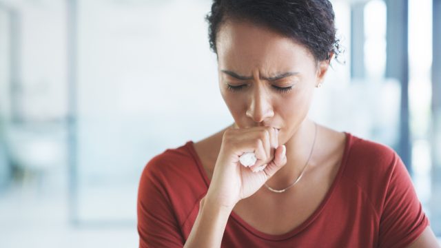 an african american woman coughing into her hand