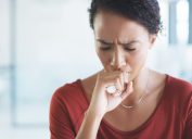 an african american woman coughing into her hand