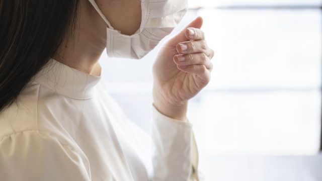 Close up face of young woman wearing mask and coughing