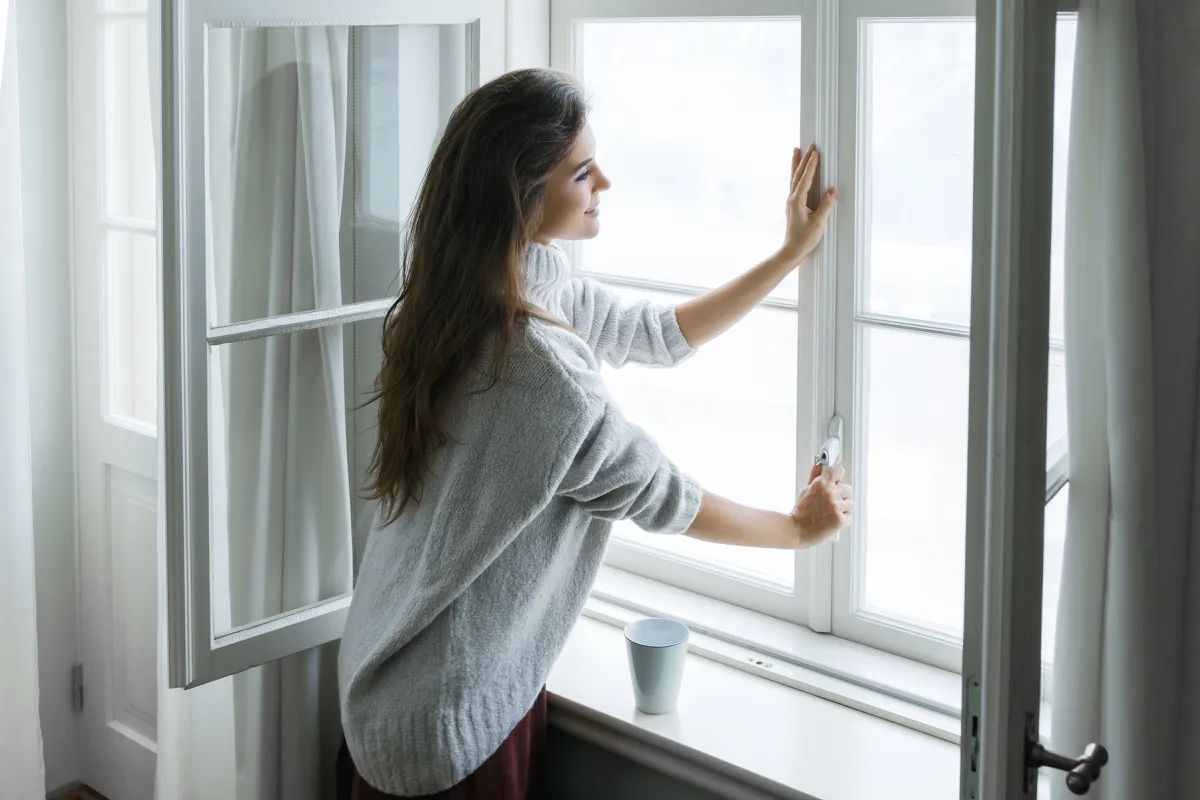brunette woman opening white window