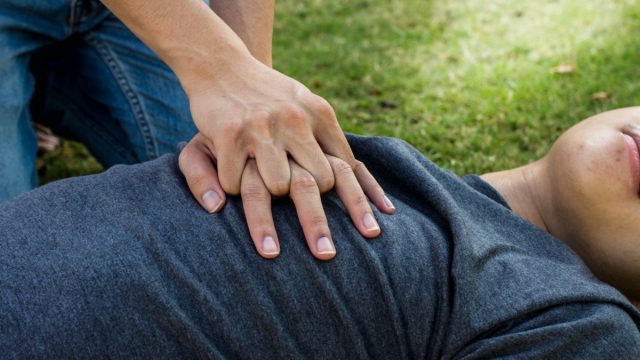 woman performing CPR on man outdoors
