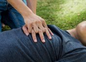 woman performing CPR on man outdoors