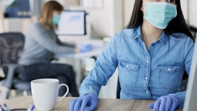 Woman in protective gloves and mask in the office