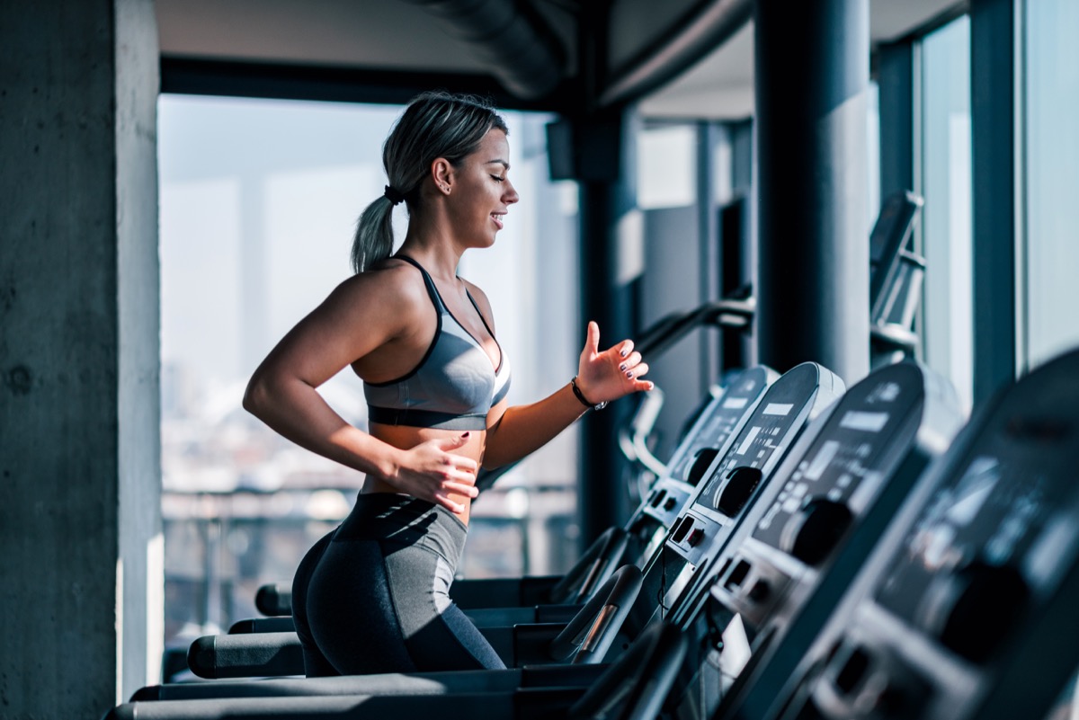 Side view of muscular woman running on treadmill.
