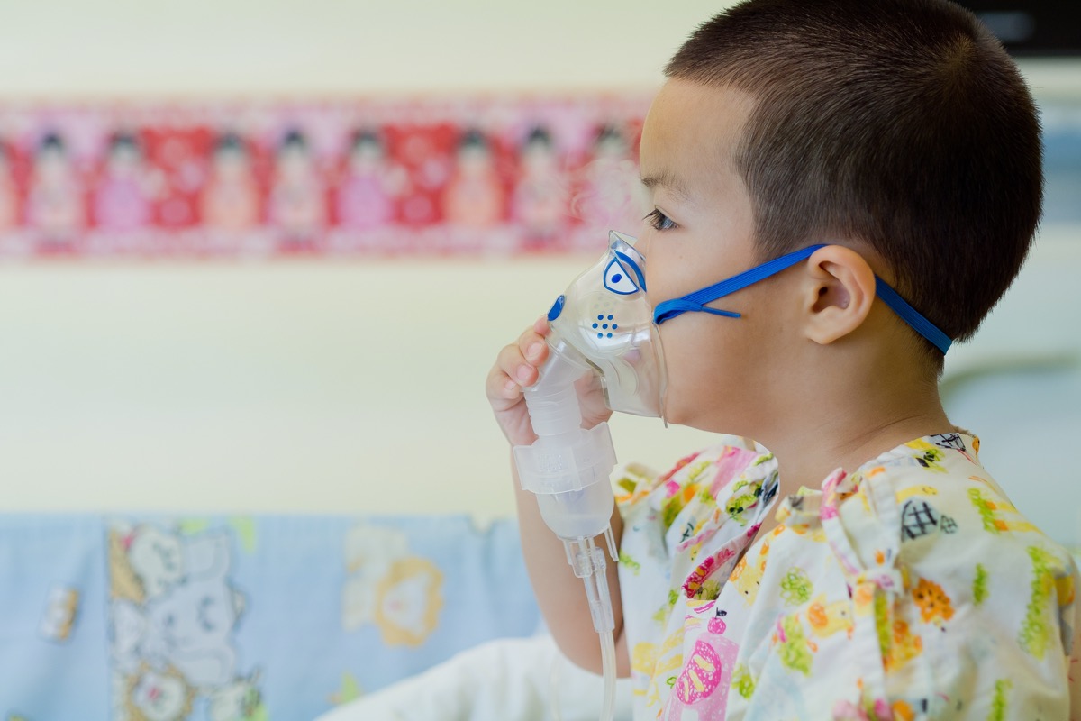 young boy using oxygen mask in hospital
