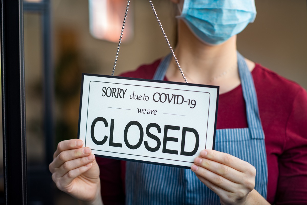 Woman in mask holding "closed" sign