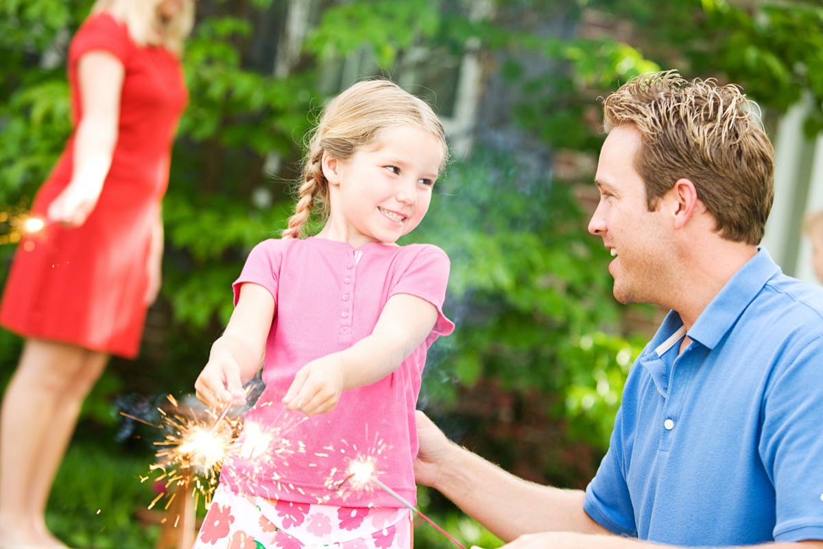 Father and daughter using sparklers