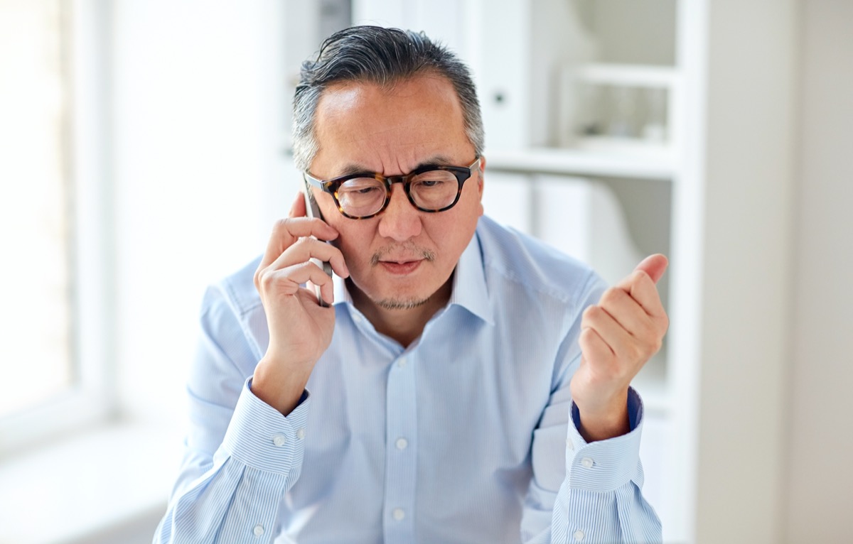 Mature Asian man in glasses on phone