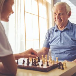 Senior white man and young woman playing chess