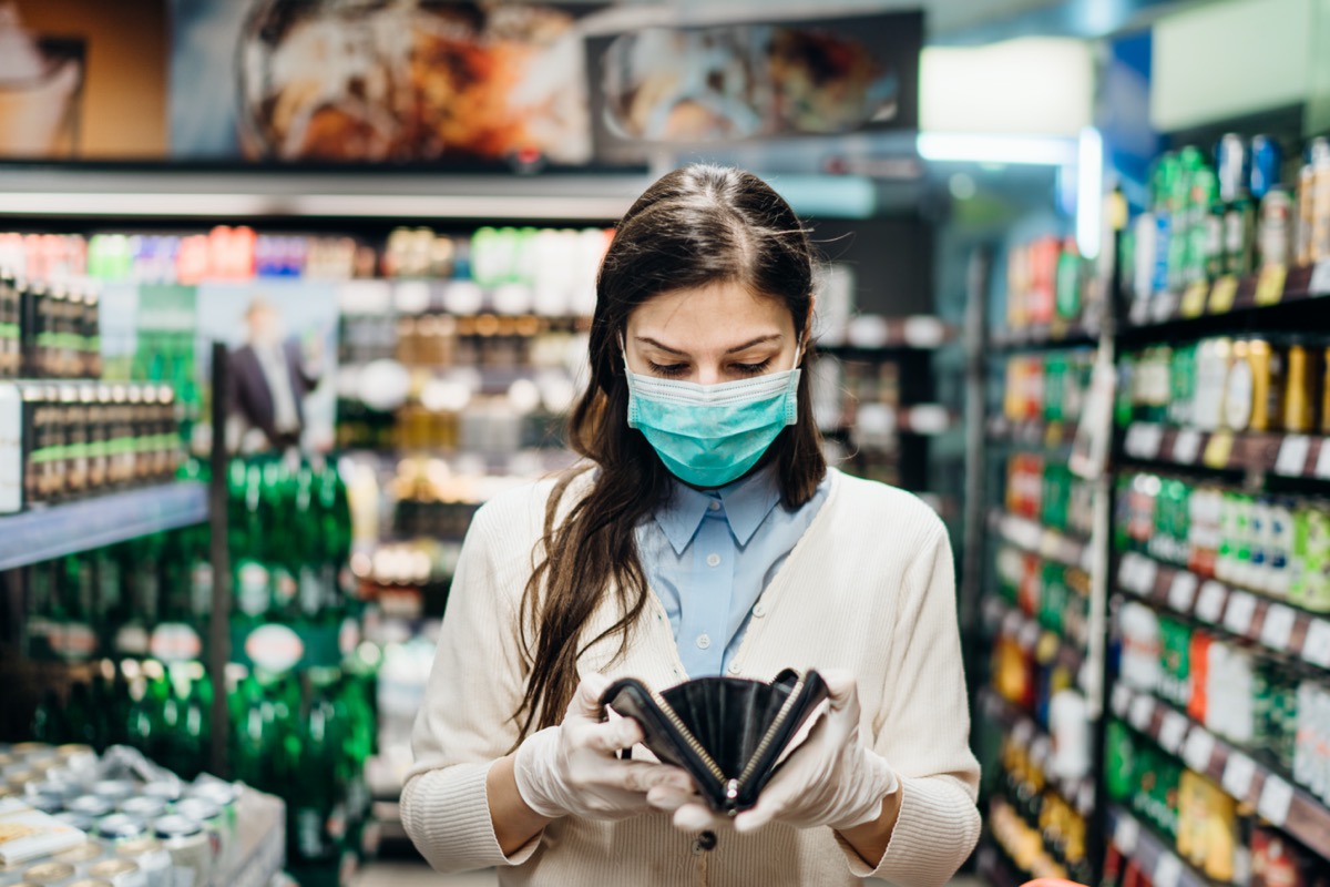 Woman in grocery store wearing a mask and looking in wallet
