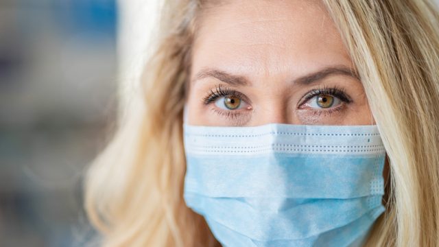 A blonde woman wearing a face mask to stop the spread of coronavirus