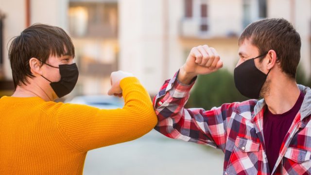 People elbow bumping in masks