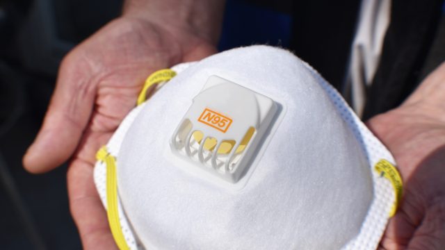 A close up of an N95 respirator protective face mask being held in someone's hands