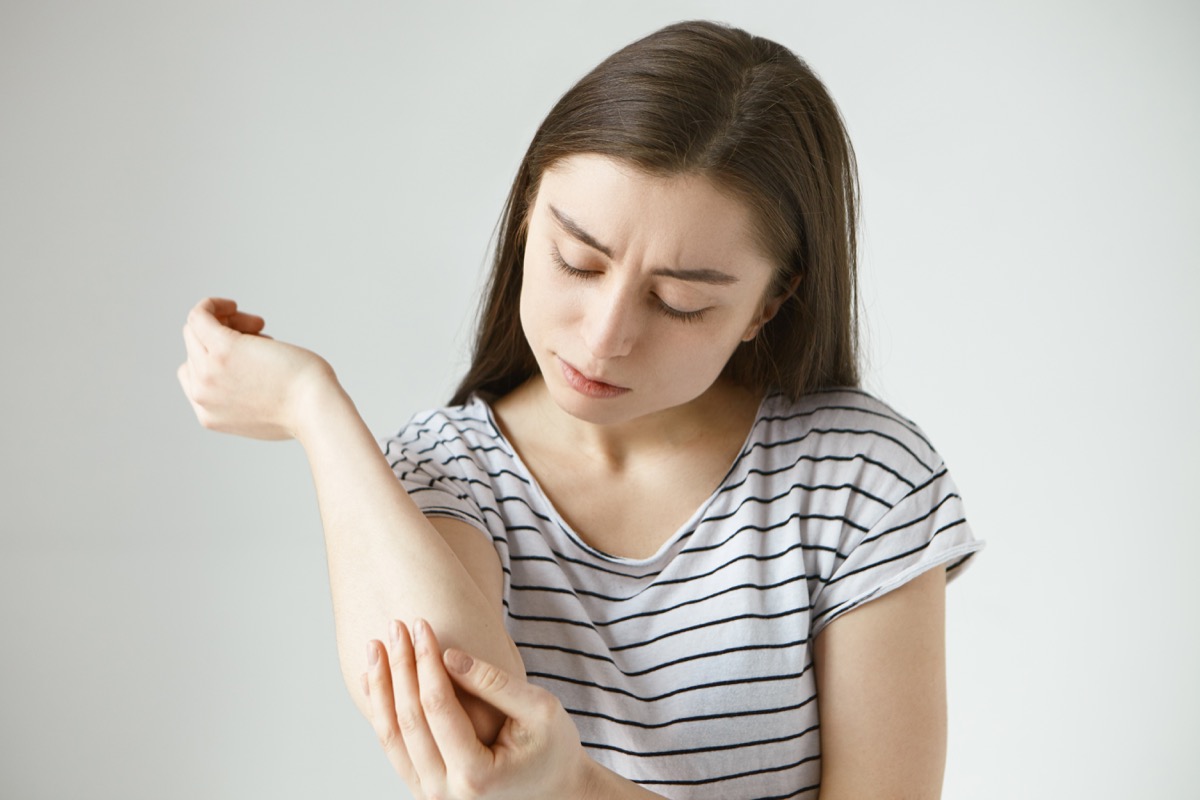 Girl looking at her elbow to see if she has a rash