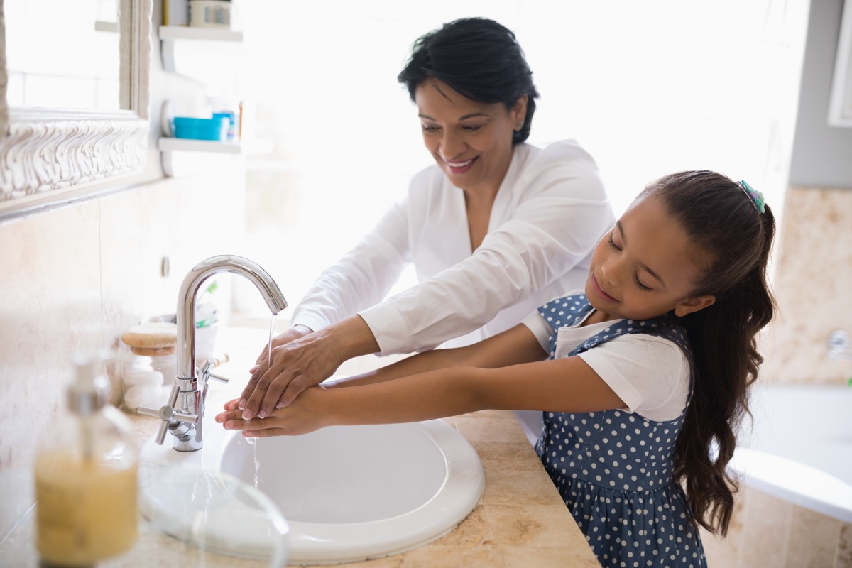 Mom helping her daughter wash her hands