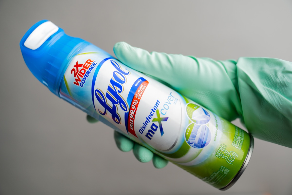 gloved hand holding lysol can