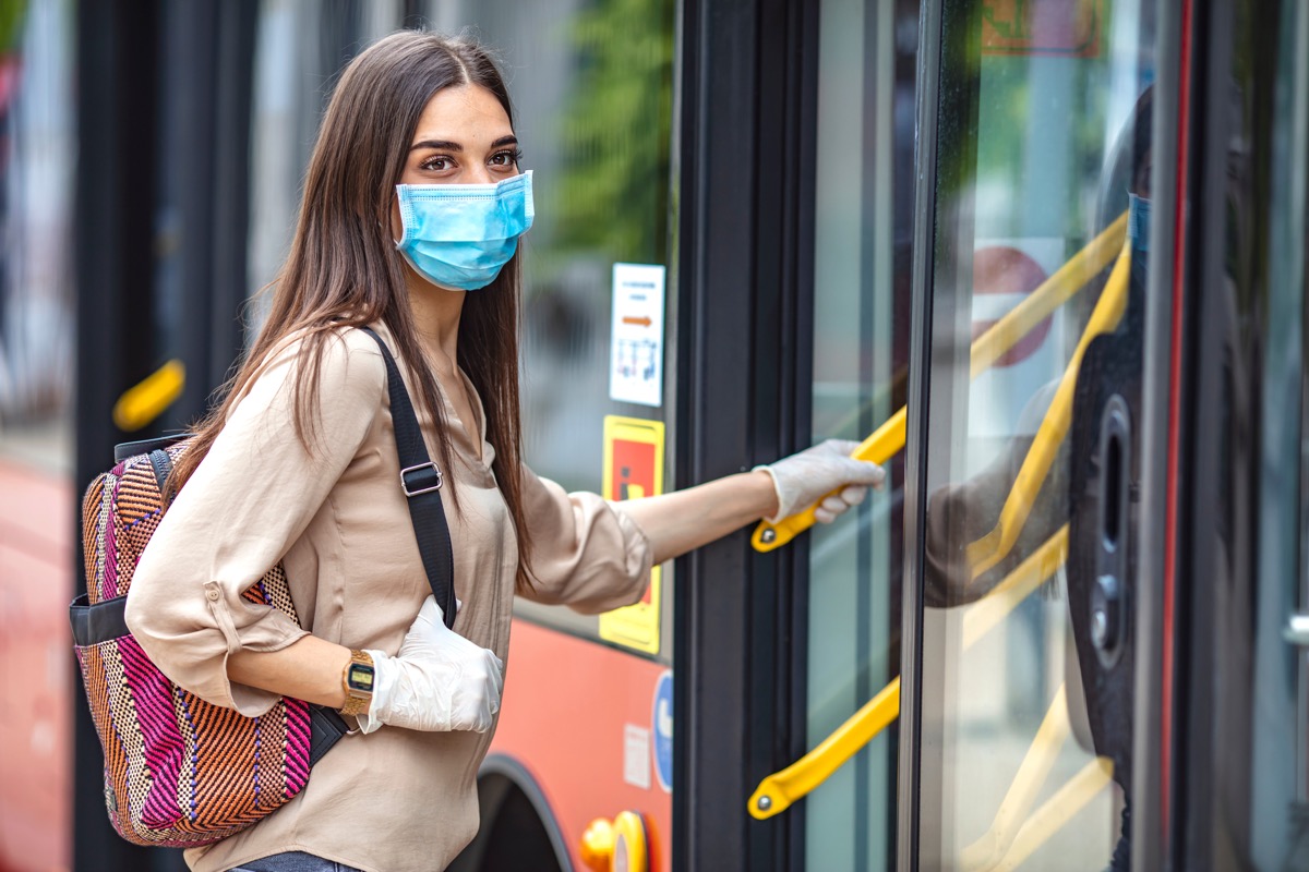 Woman wearing a face mask getting on public transportation