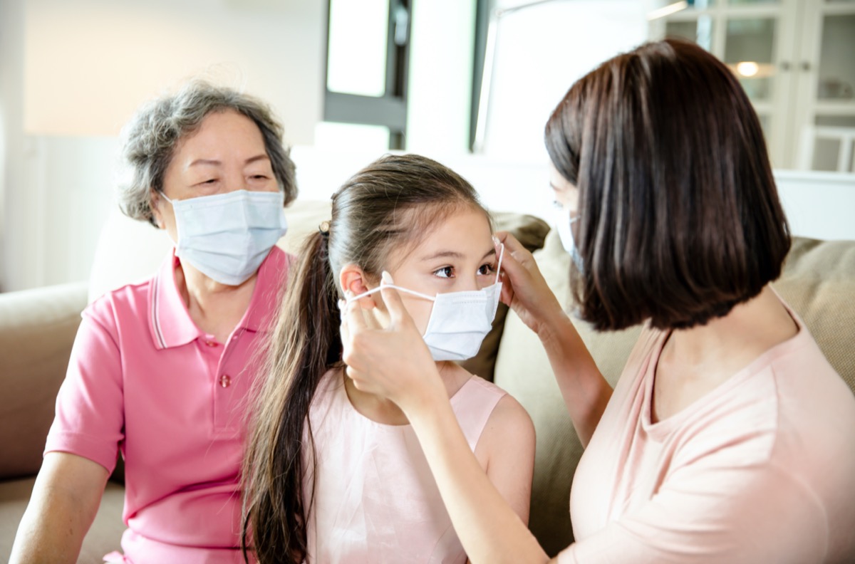 mother putting mask on young daughter