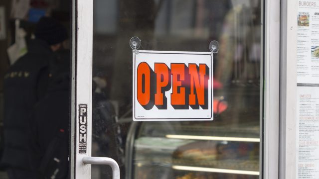 The OPEN sign is seen at the entrance to a business amid the COVID pandemic in March 2020