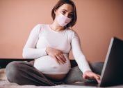 Pregnant woman with mask, using computer