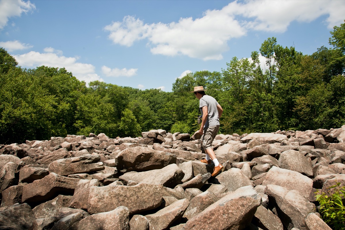 Man standing in field of boulders at Ringing Rocks State Park in Pennsylvania