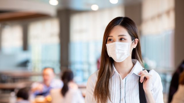 young asian woman with a face mask walking inside mall