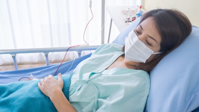 asian woman with face mask in hospital bed