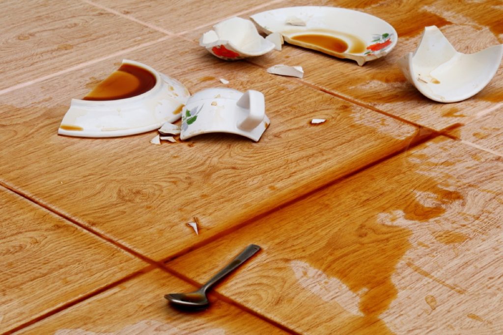 broken coffee cup and plate with spoon on the floor