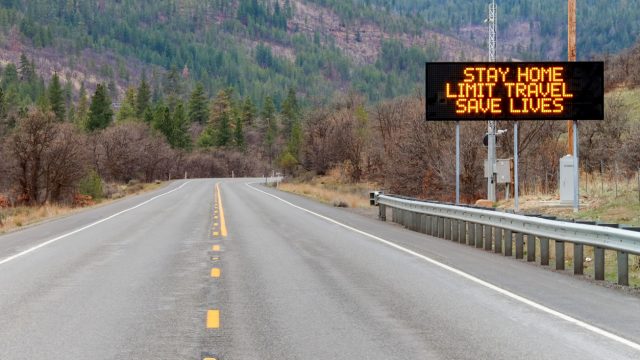 An electronic sign on the highway warning citizens to "stay home, limit travel, save lives"