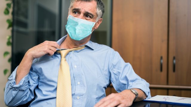 Man sweating because the temperature is hot at work while wearing a mask