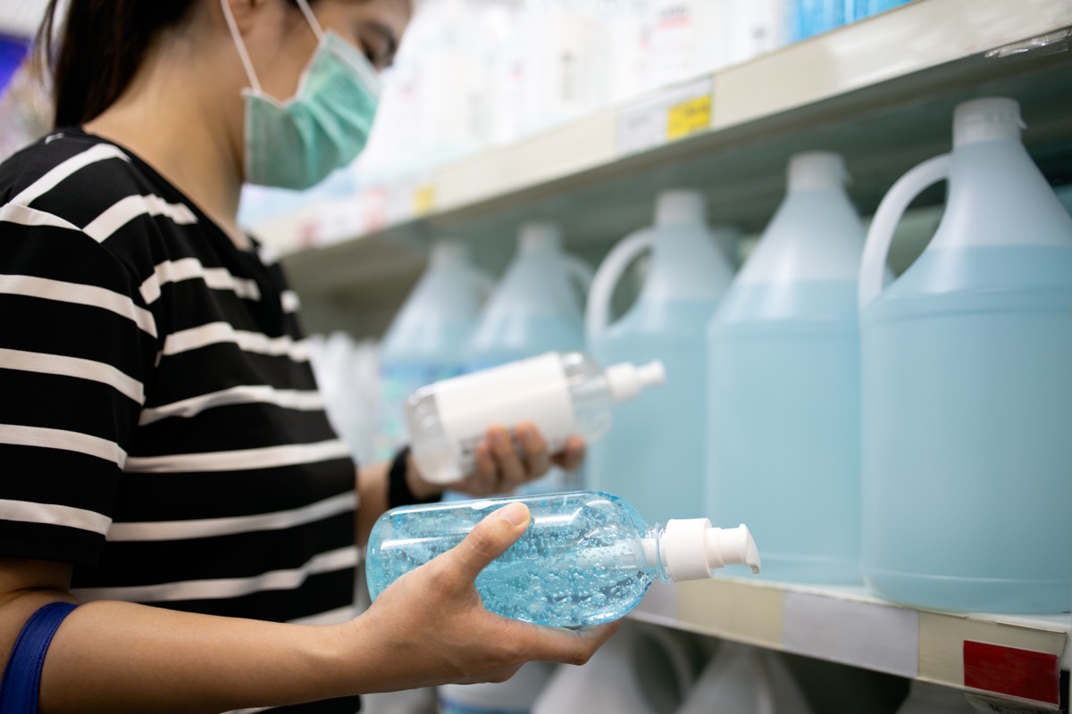 woman choosing between hand sanitizers at store