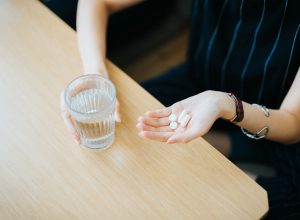 Close up of woman holding a glass of water and medication in her hand