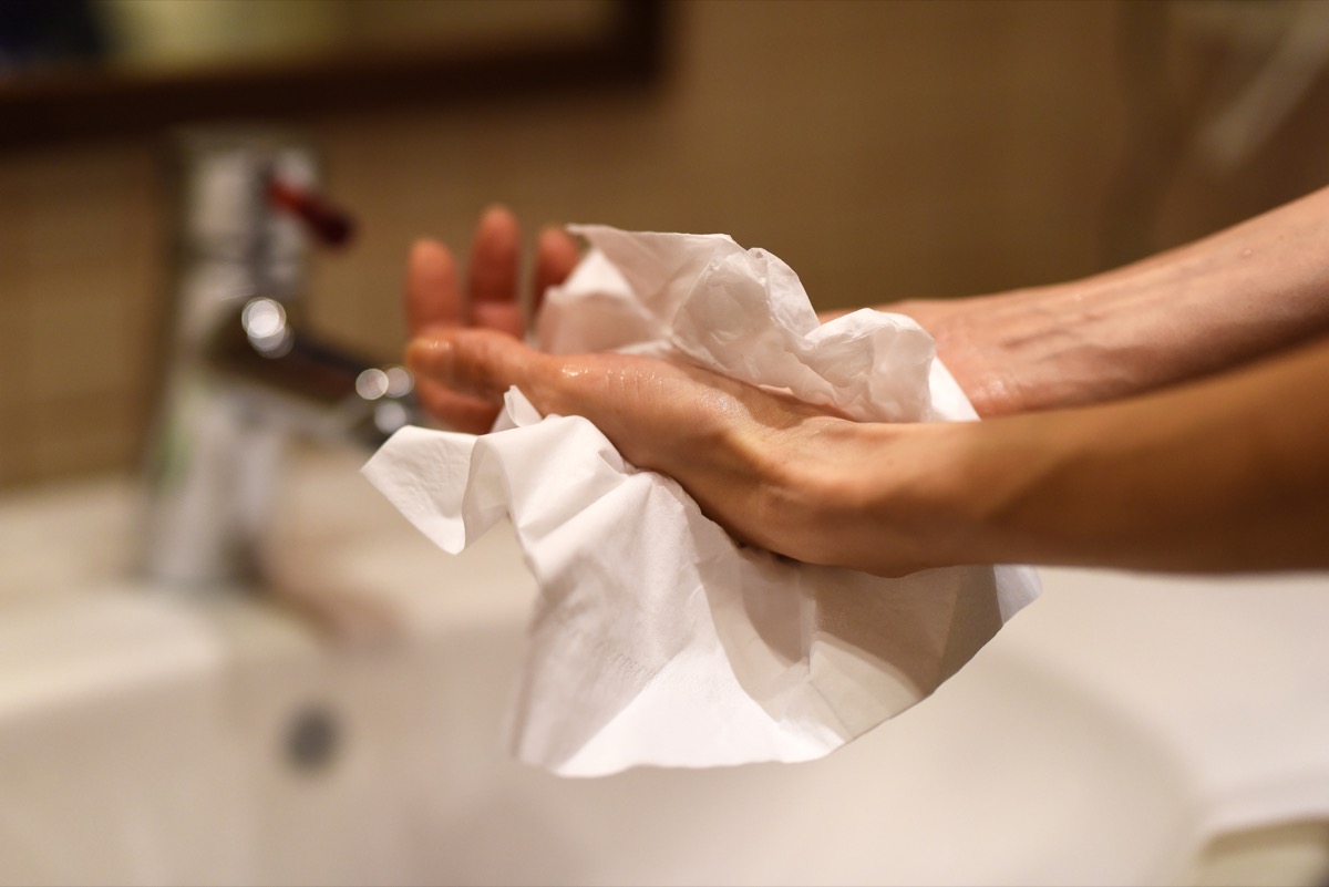 Female hands using paper towel after washing, as a protection against viruses